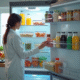 Femme ouvrant un congélateur bien organisé dans une cuisine lumineuse